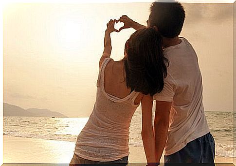 Couple-in-love-forming-a-heart-with-their-hands-on-the-beach