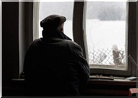 Elderly looking out the window with snow