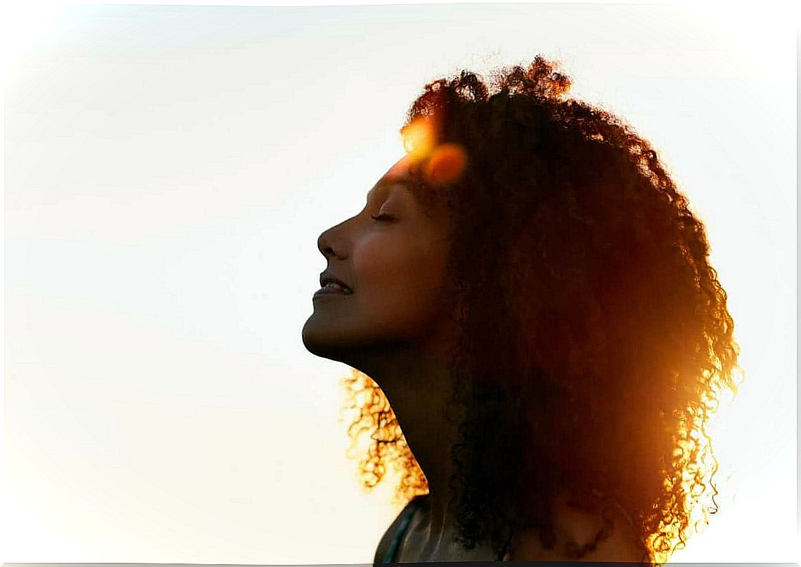 woman with eyes closed in front of the sun